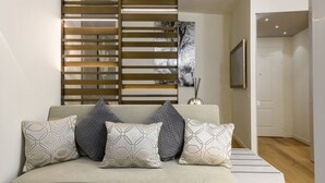 A modern living room with a sofa, patterned cushions, a decorative wall panel, and a framed picture. - Gian Giacomo Mora, 13 - Refined studio apartment downtown (Milan)
