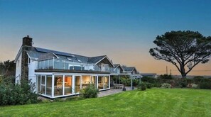 A modern two-story house with large glass windows and a well-maintained lawn. - Devon House Hot Tub Sea Views & Family Fun (Devon)