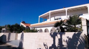 A modern building with a white facade, multiple windows, and a red-tiled roof. - Comfortable, Welcoming Family Villa Just Steps from the Sea (Avola)
