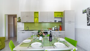 A modern kitchen with white cabinets, a dining table set for six, and a green accent wall. - Holiday Home 'Villa Anny Seafront' with Wi-Fi and Air Conditioning (Avola)