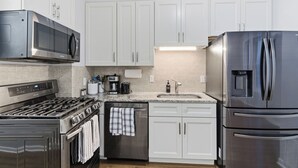 A modern kitchen with white cabinets, stainless steel appliances, a built-in oven, microwave, and refrigerator. - Cozy 2BR Apartment in Jersey City With Smart Lock (Jersey City)