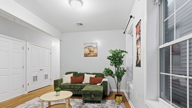 A modern living room with a green sofa, a round coffee table, and a potted plant. - Cozy 2BR Apartment in Jersey City With Smart Lock (Jersey City)