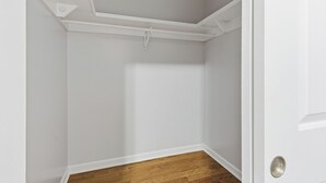 A corner of a room with white walls, a wooden floor, and a white ceiling with a vent. - Cozy 2BR Apartment in Jersey City With Smart Lock (Jersey City)