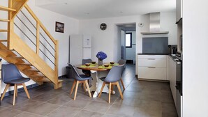 Una cucina moderna con una scala in legno, un'area pranzo con quattro sedie e un'isola cucina.