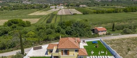 A modern two-story house with a swimming pool, a tennis court, and a well-maintained lawn.