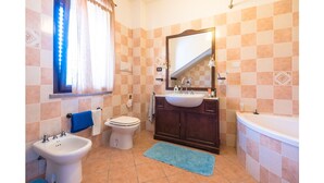 Een badkamer met toilet, bidet, wastafel en bad.