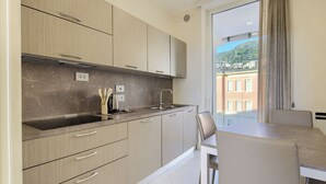 A modern kitchen with light wood cabinets, a marble backsplash, and a dining area with a table and chairs. - Luxury Seafront Apartment Private Terrace Crescent (Salerno)