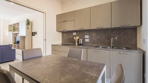 A modern kitchen with marble countertops, wooden cabinets, and a built-in sink. - Luxury Seafront Apartment Private Terrace Crescent (Salerno)