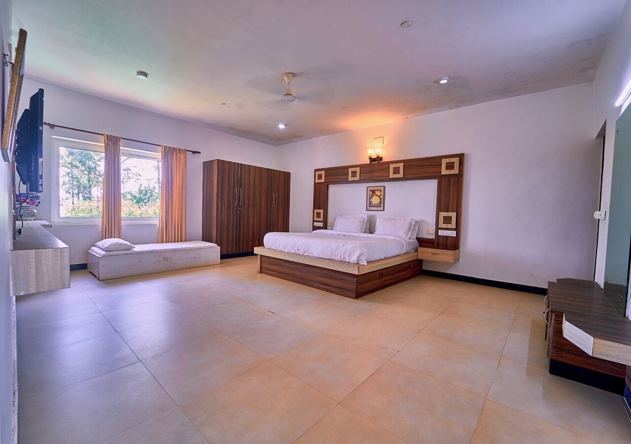 A modern bedroom with a large bed, a bedside table, a built-in bench, and a window with curtains.