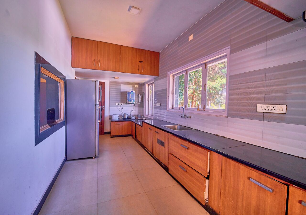 A modern kitchen with wooden cabinets, a black countertop, and a window providing natural light.