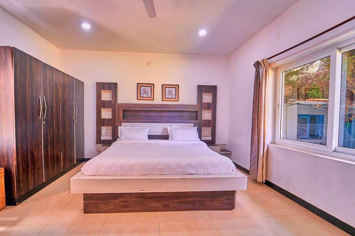 Un dormitorio con una cama grande, un armario de madera y una ventana con cortinas.