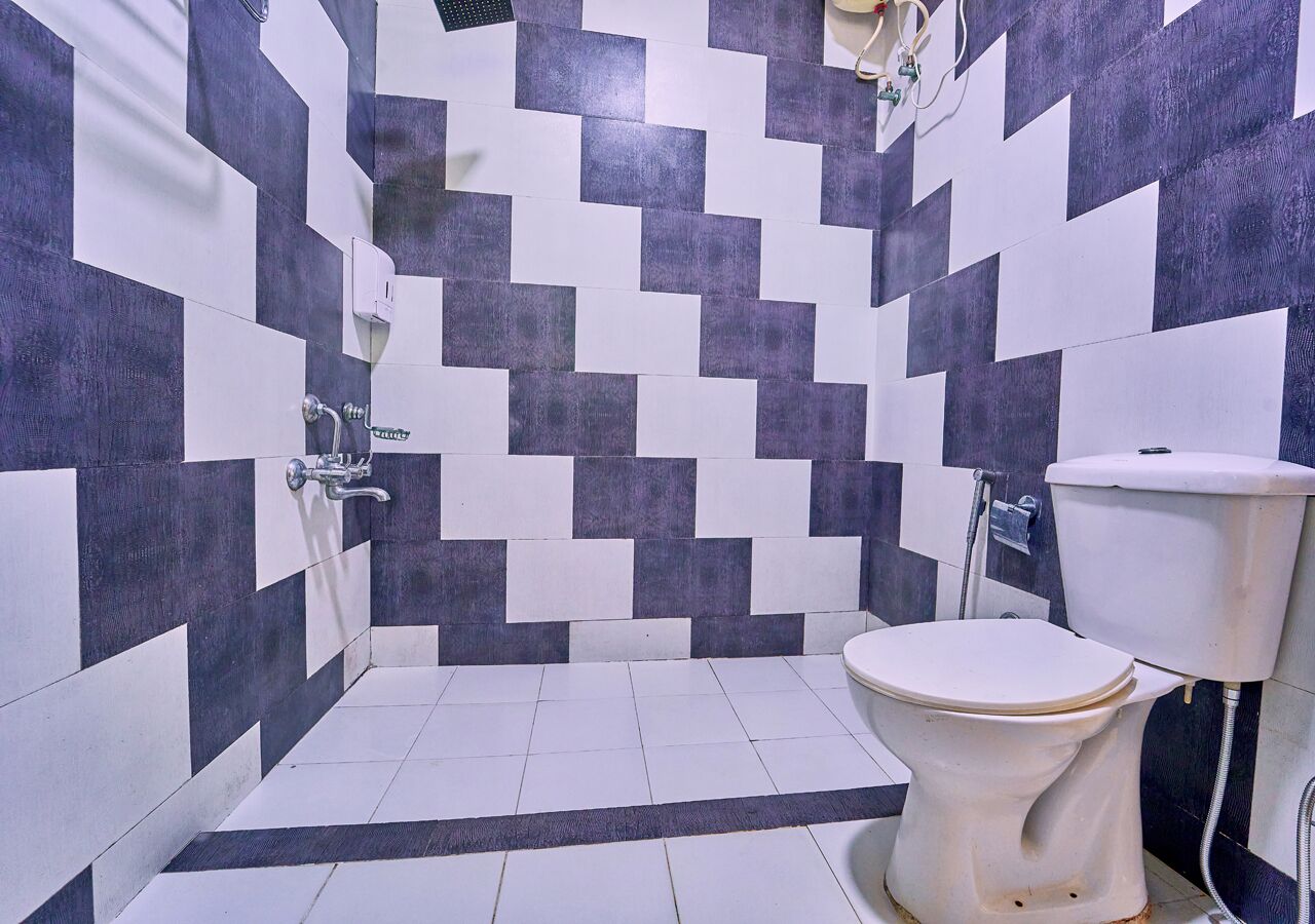 A bathroom with a black and white checkered tile pattern, a white toilet, and a shower area.
