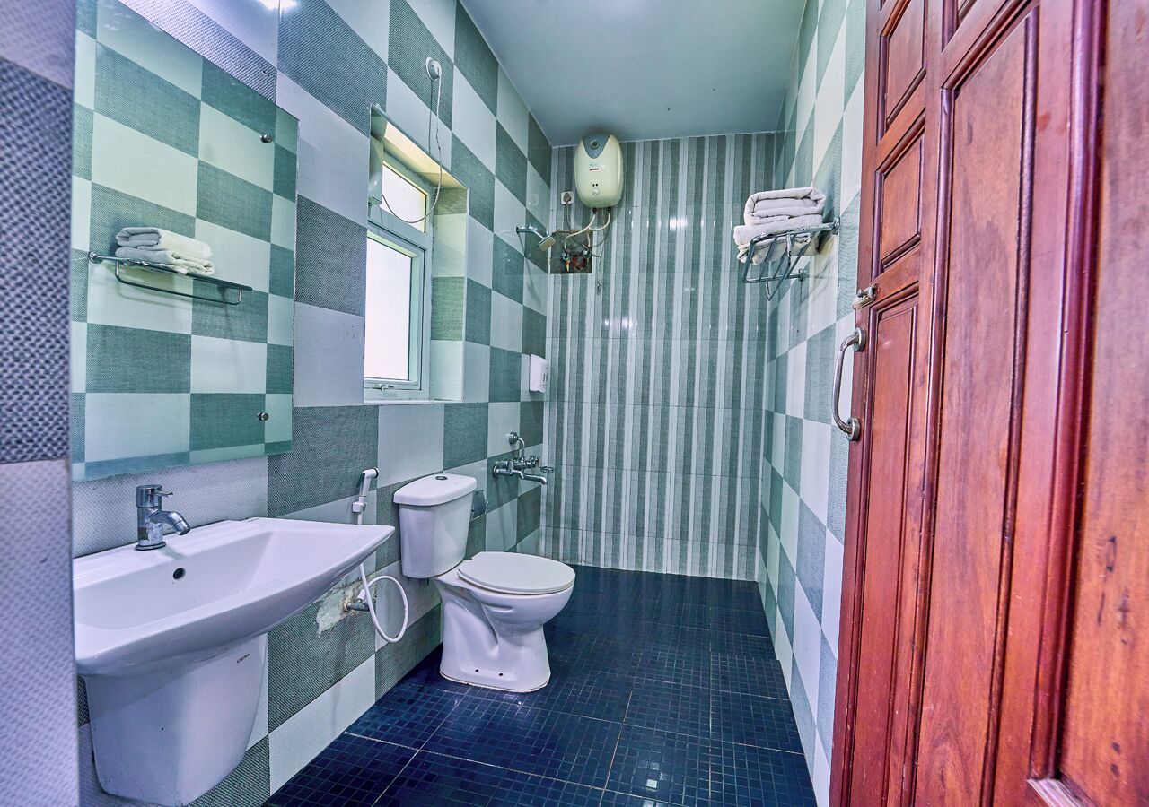 A bathroom with a checkered tile wall, a sink, a toilet, and a shower area.