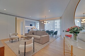 A modern living room with a sofa, chairs, a dining area, and a kitchen in the background. - NEW Beach Apartment in Quarteira (Loulé)