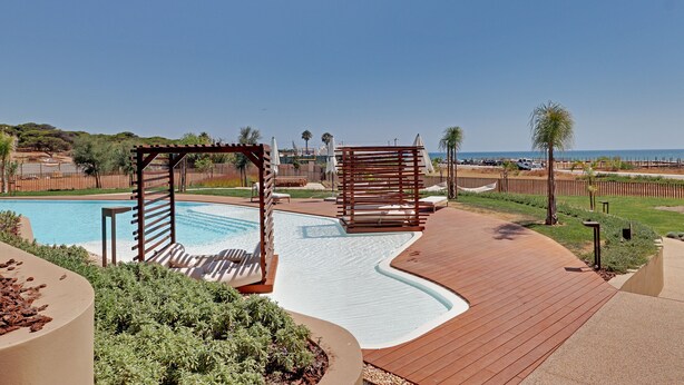 Ein Poolbereich mit Holzterrasse, Liegestühlen und einer Pergola.