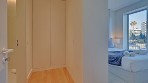 Ein Hotelzimmer mit großem Fenster, einem Bett mit weißer Bettwäsche und Holzboden.