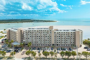 Ein mehrstöckiges Hotel mit Parkplatz und Blick auf den Strand.