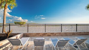 A patio with lounge chairs and a view of the beach. - SUMMER DISCOUNT! Beachfront 2B/2B Vacation Condo Carlos Pointe 221. Amazing Views! EVERYTHING BRAND NEW! (Fort Myers Beach)