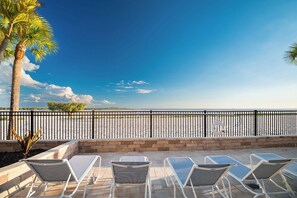 A patio with lounge chairs and a view of the beach. - SUMMER DISCOUNT! Beachfront 2B/2B Vacation Condo Carlos Pointe 221. Amazing Views! EVERYTHING BRAND NEW! (Fort Myers Beach)