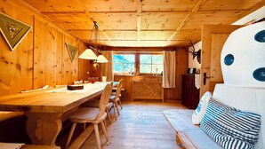 L’intérieur d’un chalet accueillant, avec une table à manger en bois, des chaises, un banc et un grand élément décoratif blanc sur le mur.