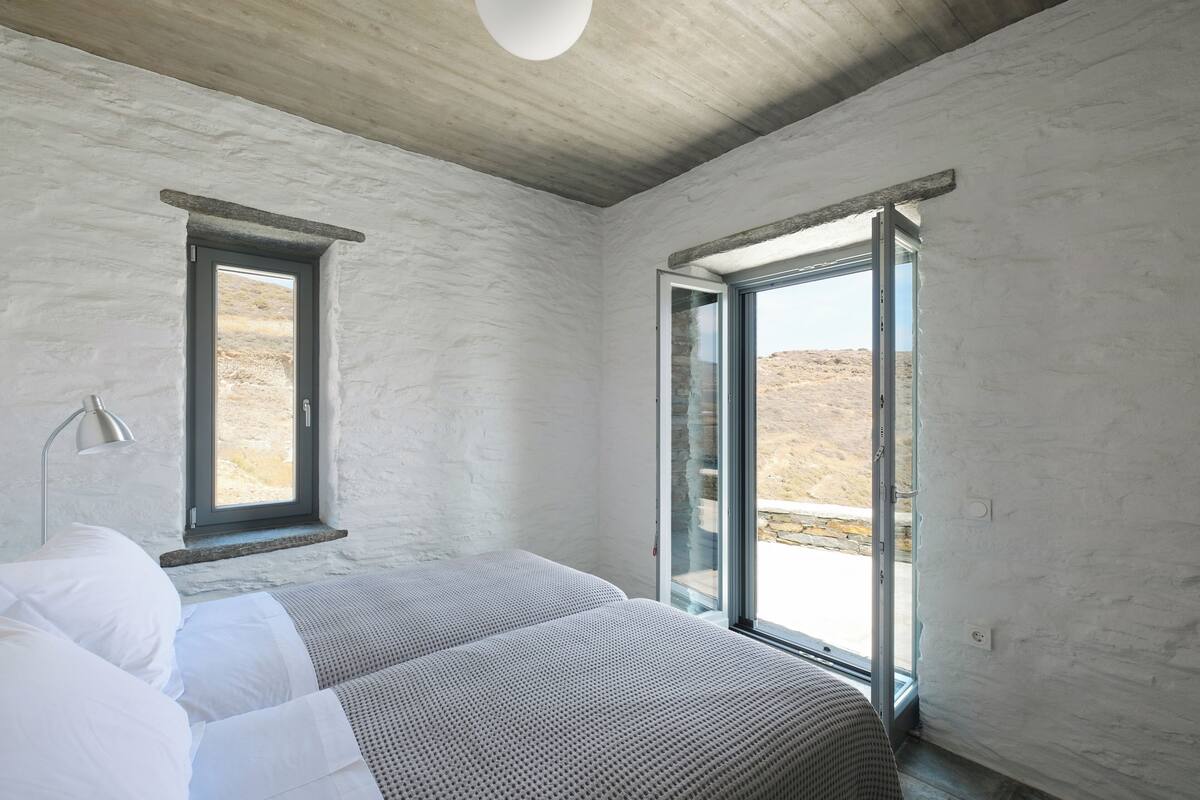 A bedroom with a bed, a window, and a door leading to an outdoor area.