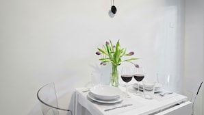 A minimalist dining setup with a white table, clear glassware, and a vase with flowers. - Italianway Comfort - Gomes 5 (Milan)