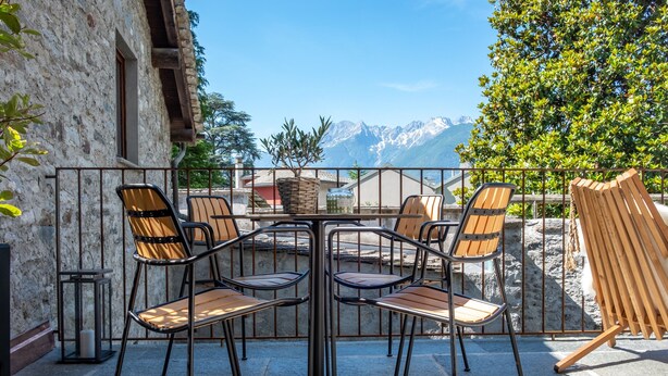Eine Terrasse mit Tisch, Stühlen, einer Laterne und Blick auf Berge.