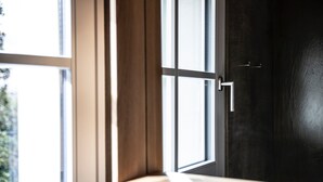 Eine dunkle Holztür mit silberner Klinke und einem Fenster mit weißen Rahmen.