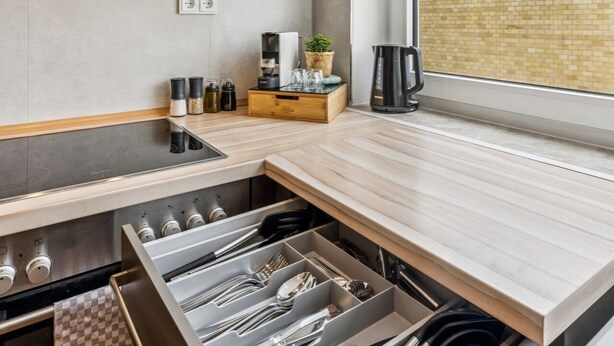 Una cocina moderna con horno empotrado, campana extractora de acero inoxidable y encimera de madera.