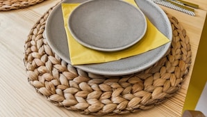 Una mesa dispuesta con platos, una copa y un florero con flores amarillas.
