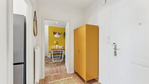 Un pasillo con un armario amarillo, una puerta blanca y un refrigerador.