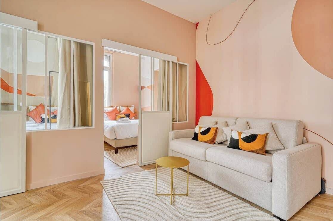 A modern living room with a sofa, a small round table, and a large mirror.