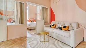 A modern living room with a sofa, a small round table, and a large mirror. - Confortable 3 pièces avec climatisation (Paris)