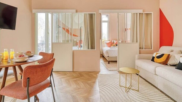 A modern hotel room with a dining area, a sofa, and a TV. - Confortable 3 pièces avec climatisation (Paris)