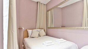 A bedroom with a bed, a mirror, and a window with curtains. - Charmant, confortable et climatisé - Paris 17 (Paris)