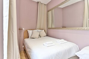 Ein Schlafzimmer mit Bett, Spiegel und einem Vorhangfenster.