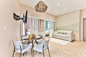 Ein modernes Wohnzimmer mit einer Couch, einem Essbereich mit Tisch und Stühlen sowie einem großen Fenster.