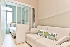 Ein modernes Wohnzimmer mit einer Couch, Kissen und einer Schiebetür zu einem Balkon.