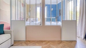 Quarto com duas camas, um sofá e vista pela janela com cortina.