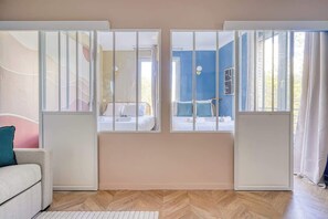Ein Zimmer mit zwei Betten, einem Schlafsofa und Blick durch ein Fenster mit Vorhang.