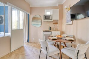 Eine moderne Küche mit Essbereich, großem Fenster und Flachbildfernseher.