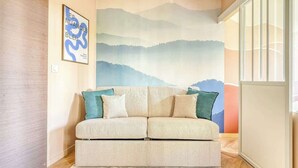 Uma sala de estar moderna com um sofá, um mural grande na parede e piso de madeira.
