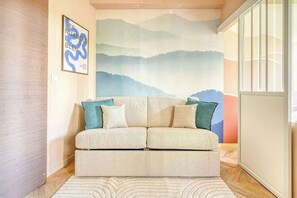 Ein modernes Wohnzimmer mit einer Sofagarnitur, einer großen Wandmalerei und Holzboden.