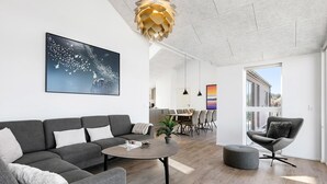 Un salon moderne comprenant un canapé, une table basse et un coin repas avec des chaises et une table.