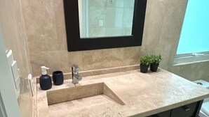 A bathroom with a beige countertop, a black sink, a mirror, and a small potted plant. - Arquimedes Calm - Lovely 1BR in Polanco (Mexico City)