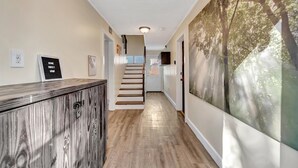 A hallway with a wooden floor, a staircase, and a wall with a forest mural. - Swann Ave House 4B 3B Sleeps 10 Near Hyde Park (Tampa)