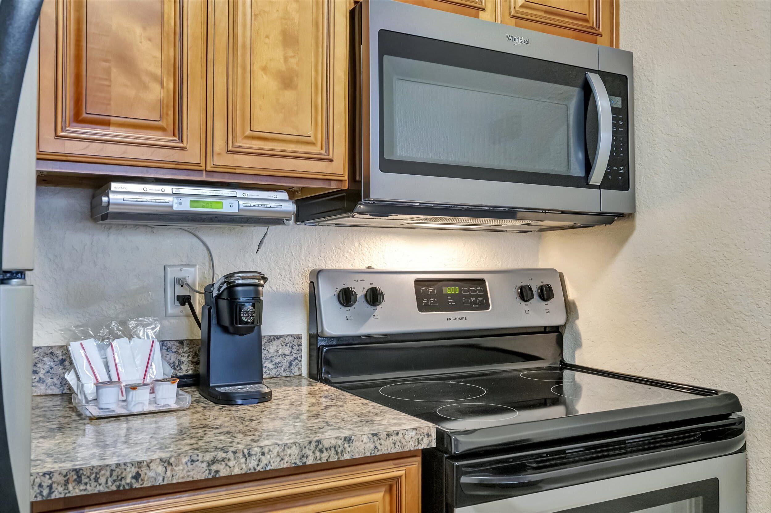 A kitchen with a microwave, coffee maker, and stove.