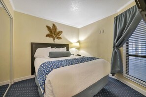 Une chambre d’hôtel comprenant un lit, une table de chevet, une lampe, un tableau décoratif et une fenêtre avec des rideaux.