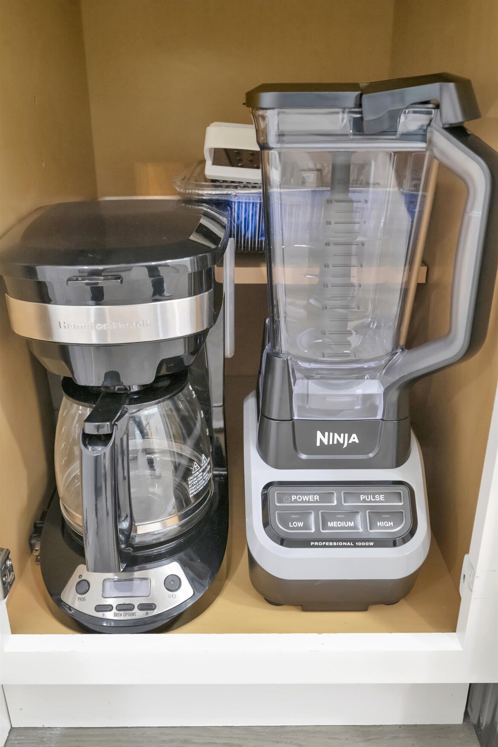 Une machine à café et un mixeur dans un placard de cuisine.