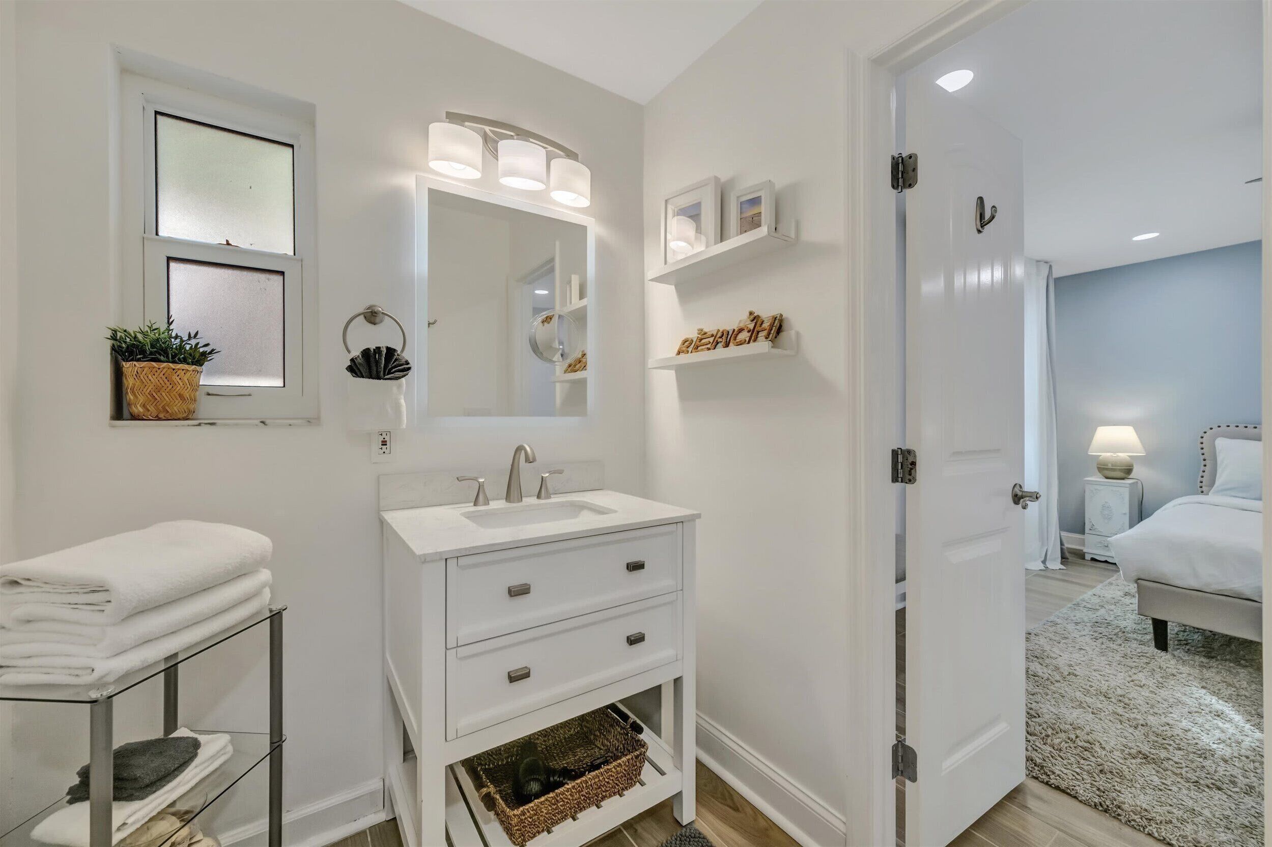 A modern bathroom with a white vanity, a large mirror, and a shower area visible through an open door.